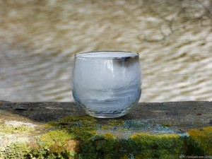 Le verre-bougie sur le banc, sur fond d'eau