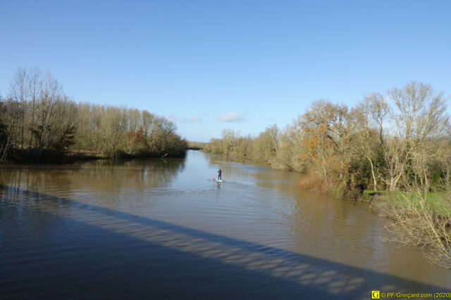 Il s'éloigne en pagayant sur son paddle