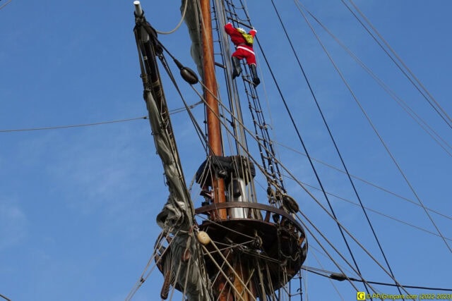 Père Noël grimpant à un mât de bateau